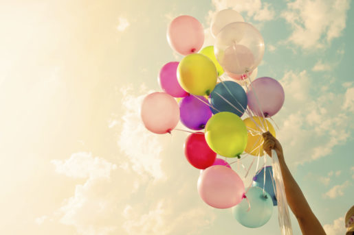 Girl's hand holding colorful balloons.