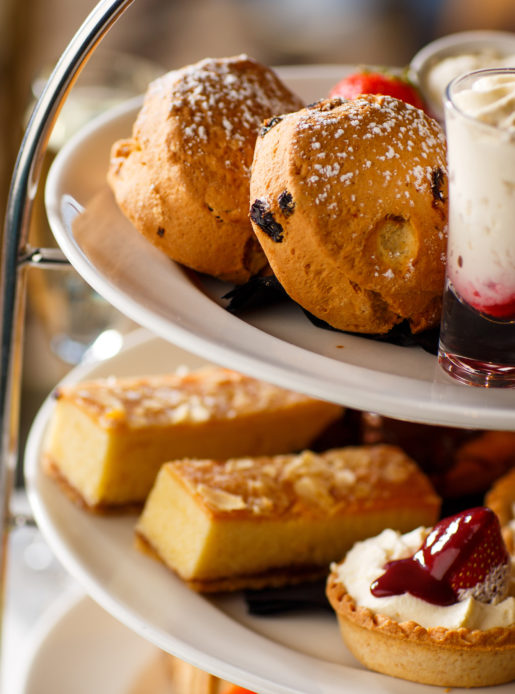 Afternoon tea with scones, cakes and dessert shots on a layered cake stand.