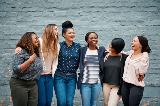 Portrait of a diverse group of young women standing together against a gray wall outside