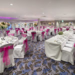 Angled view of the lakeside suite set for a wedding with pink lighting at mercure gloucester bowden hall hotel